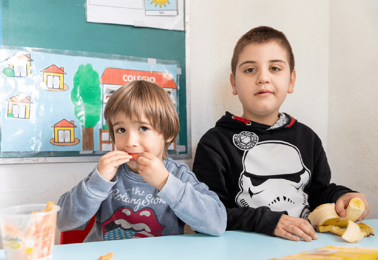 Dos niños mirando a cámara mientras toman un almuerzo saludable