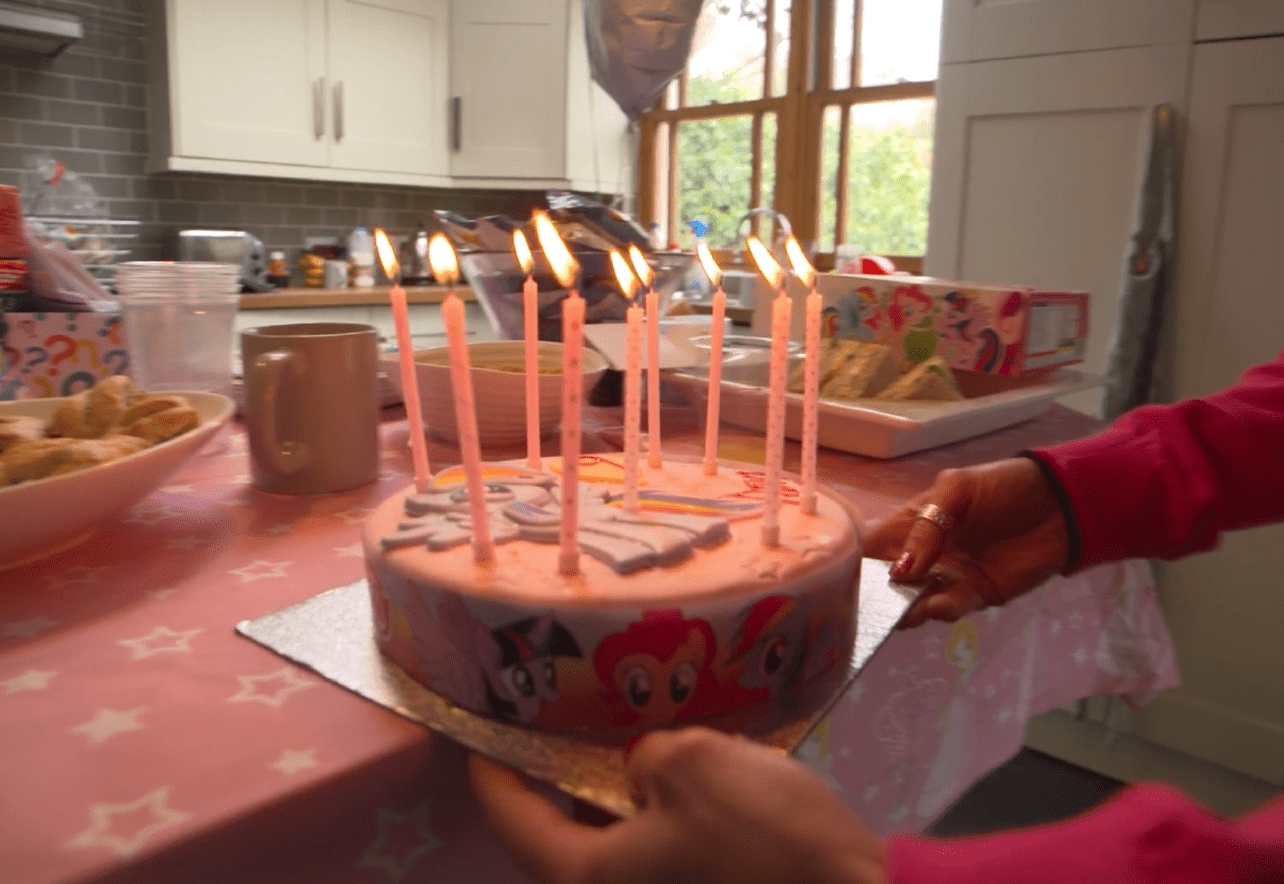 Manos sosteniendo tarta de cumpleaños infantil con velas encendidas