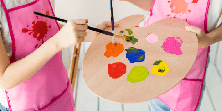Dos niños con una paleta de pintura y pinceles en sus manos