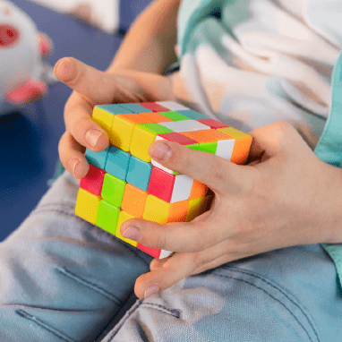 Miniatura de manos de un niño jugando con un cubo de Rubik