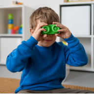 Niño tapándose los ojos con una pieza de juguete verde