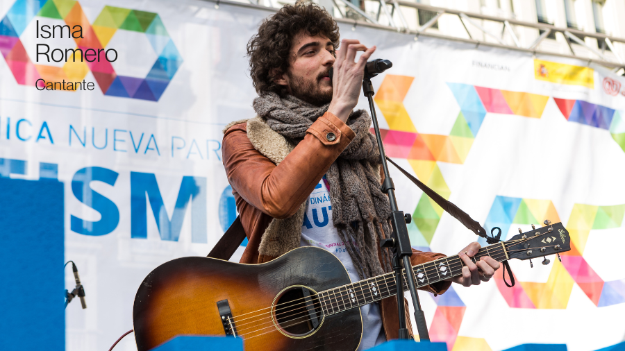 El cantante Isma Romero cantando sobre un escenario con su guitarra