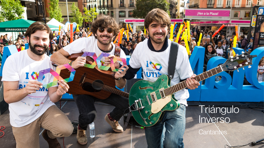 El grupo de música Triángulo Inverso posando sobre el escenario cogiendo un infinito multicolor
