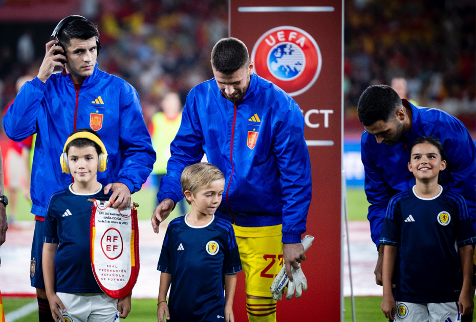Tres jugadores de la sección masculina de fútbol junto a tres menores con autismo en el campo de fútbol
