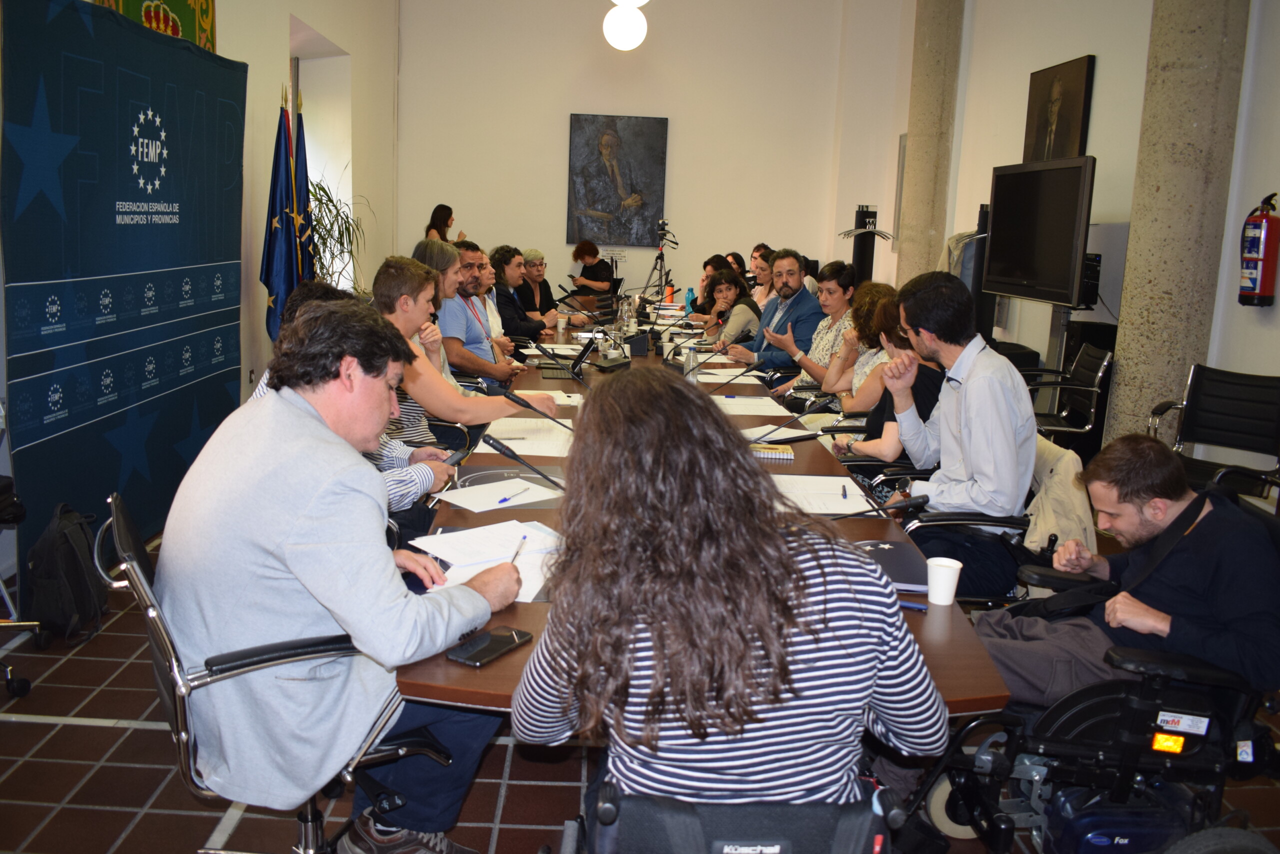Varias personas, hombres y mujeres, sentados alrededor de una mesa alargada, debaten sobre accesibilidad en la sede la de Federación Española de Municipios y Provincias