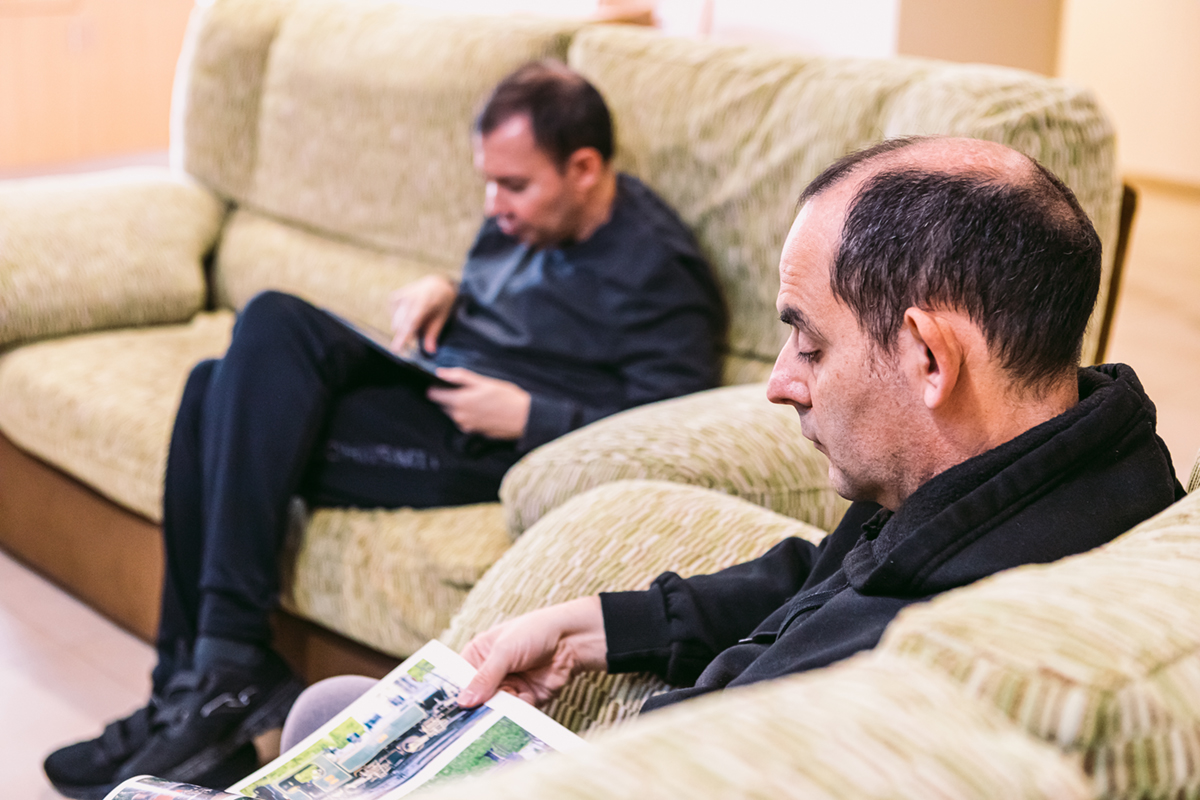 Dos hombres con autismo sentados en sofás leyendo