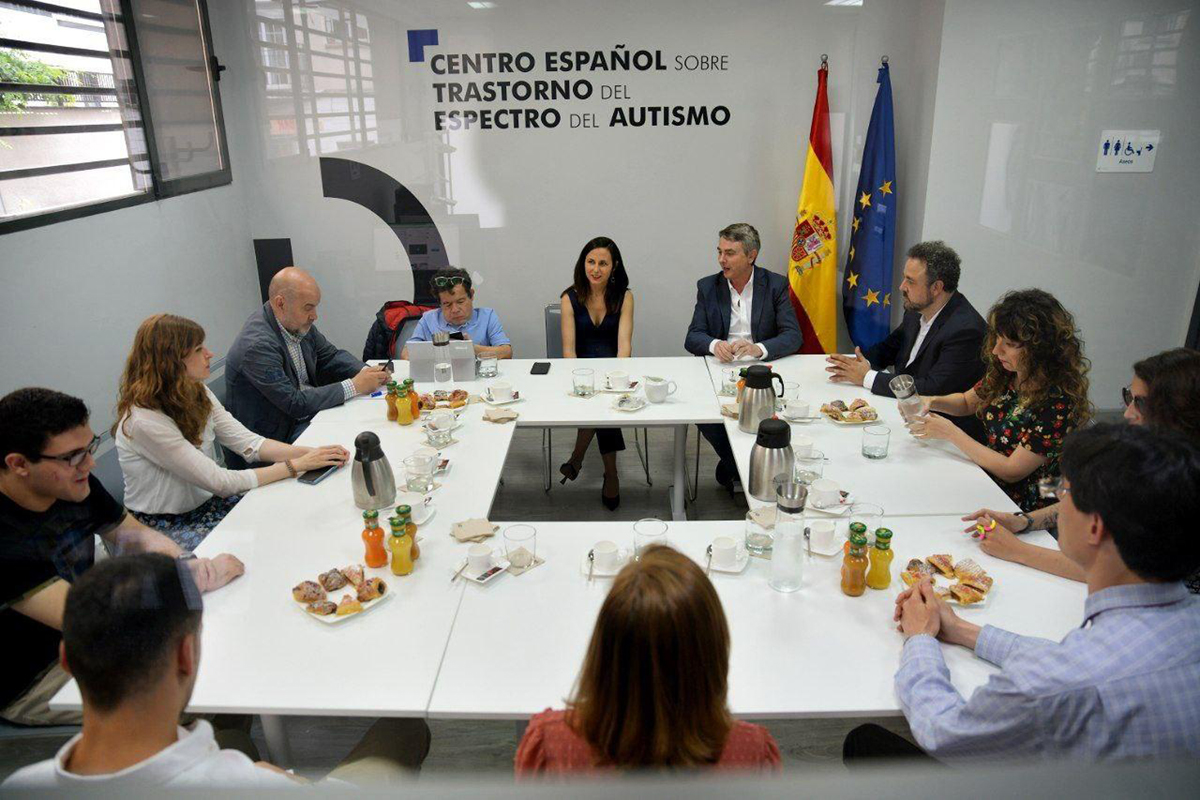 Varias personas reunidas con la Ministra de Derechos Sociales alrededor de una mesa en el Centro Español sobre trastorno del espectro del autismo