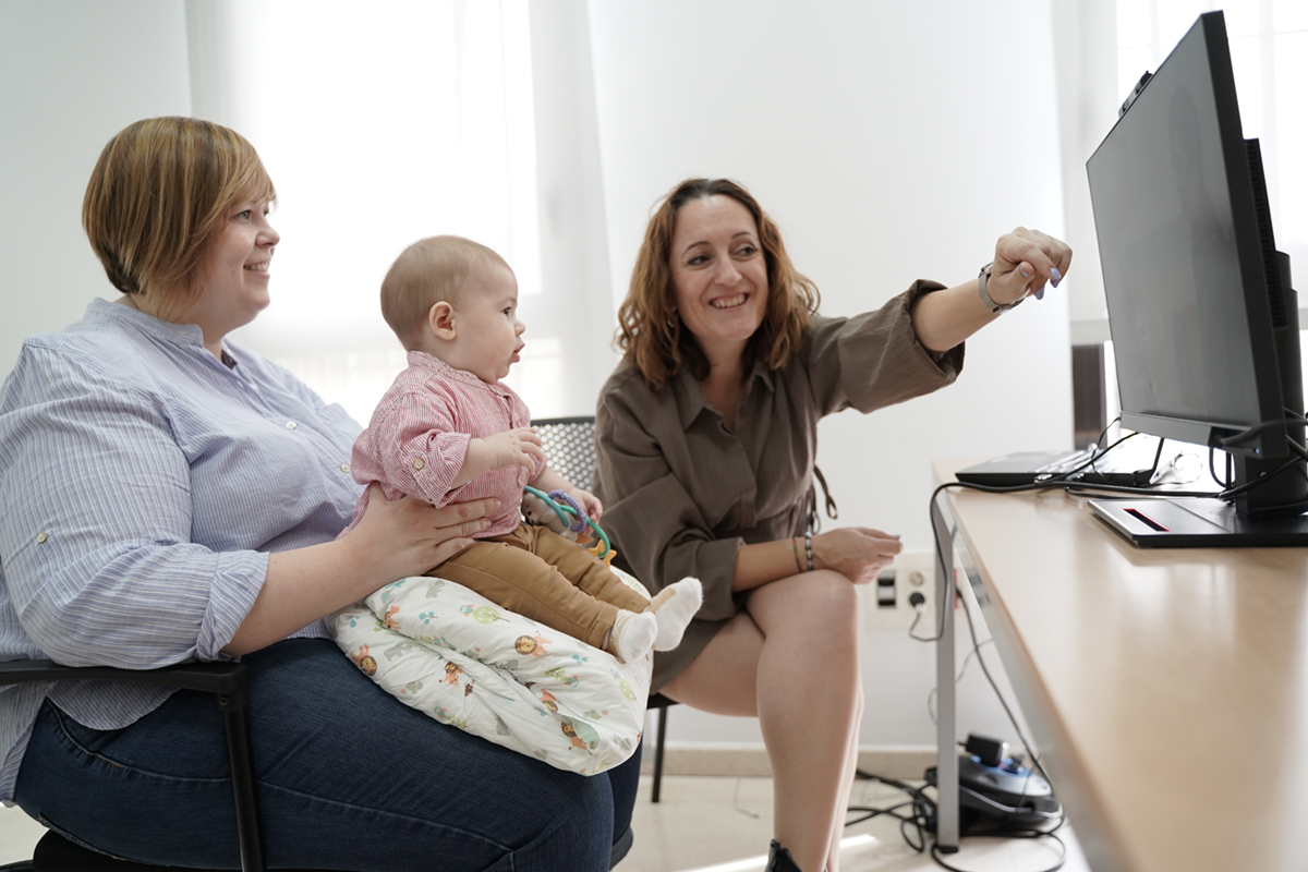 Un bebé con su madre y una profesional realizando el eye tracker de detección precoz