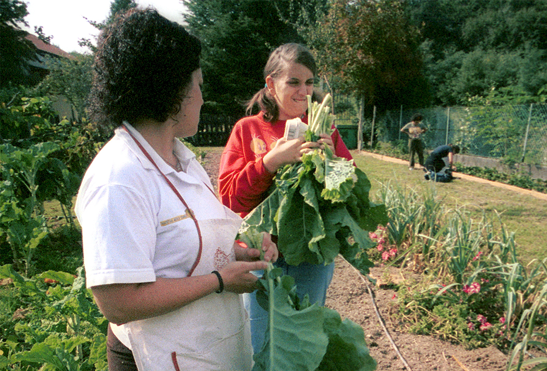 Dos mujeres autistas recolectando vegetales en un huerto