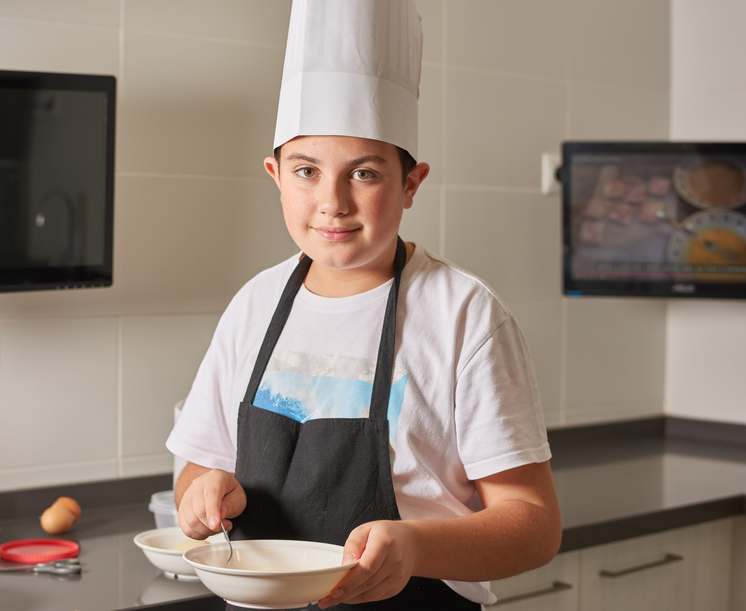 Un niño con autismo vestido con delantal y gorro de chef cocinando