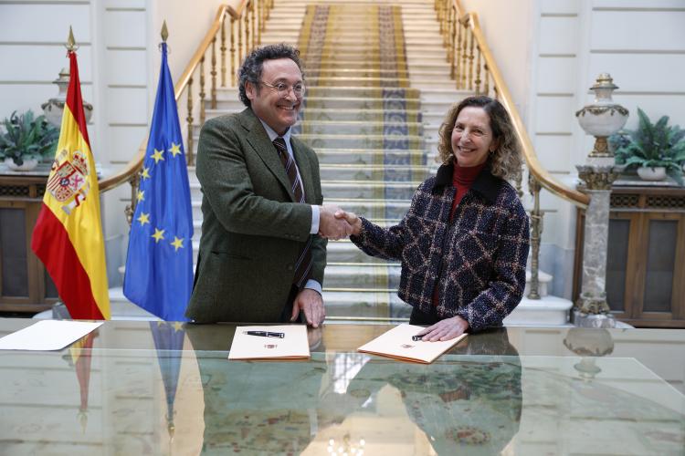 El fiscal general y la vicepresidenta de Autismo España en la firma de un convenio dándose la mano