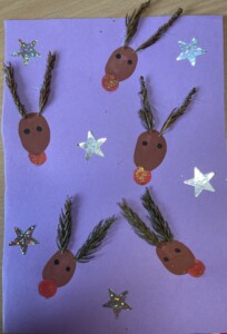 Tarjeta de navidad morada con dibujos de renos y estrellas