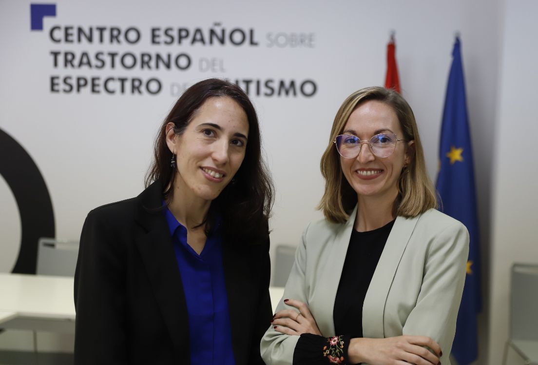 Fotografía de las dos mujeres que coordinan el Centro Español de Autismo. al fondo el rótulo del Centro y las banderas de España y la Unión Europea.