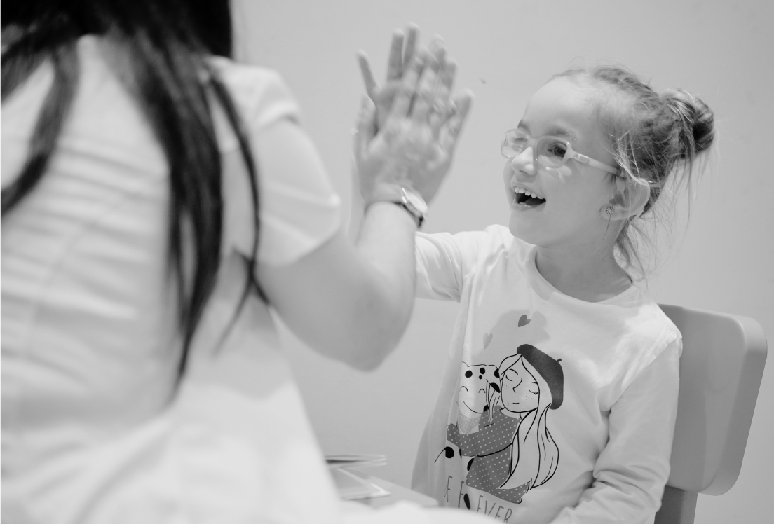 Una niña choca la mano de una mujer y sonríe