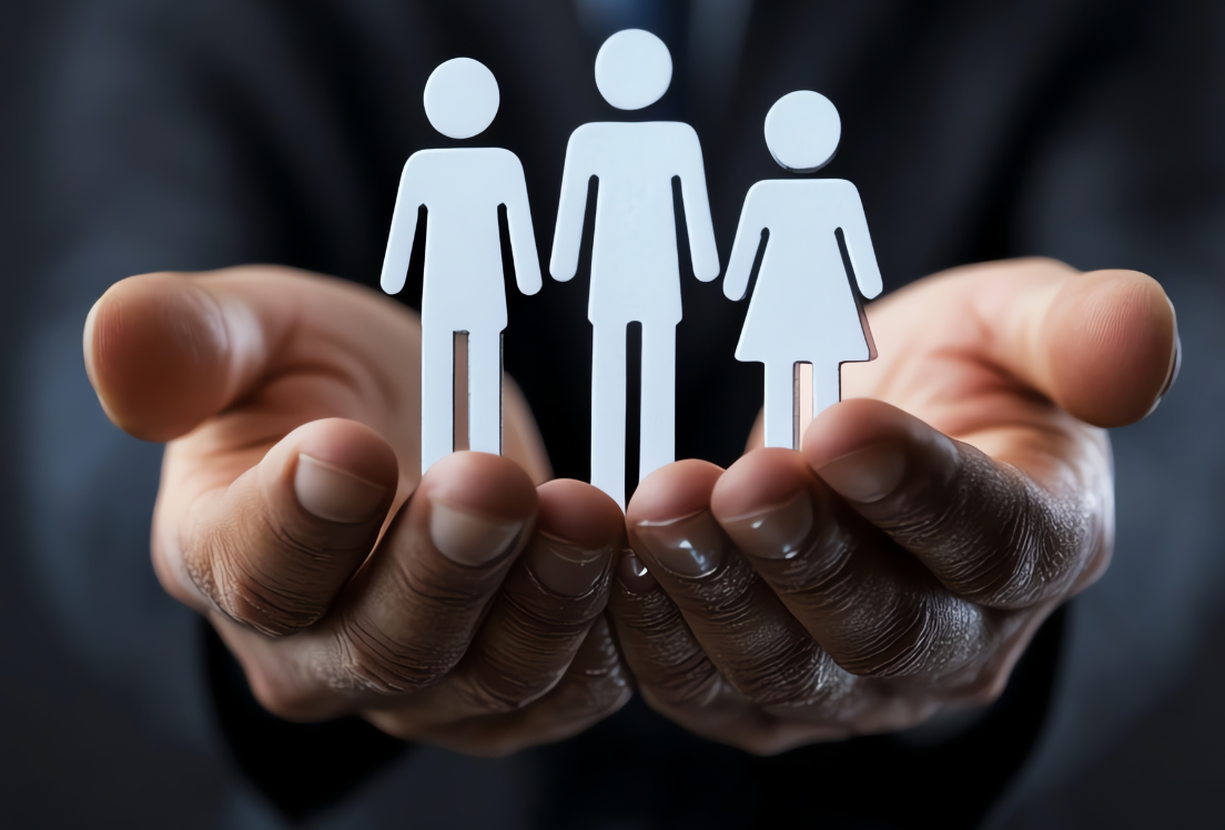 Unas manos sostienen unas figuras que representan una familia