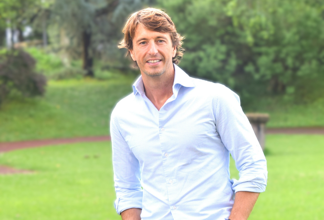 Hombre rubio vestido con una camisa posa en un jardín