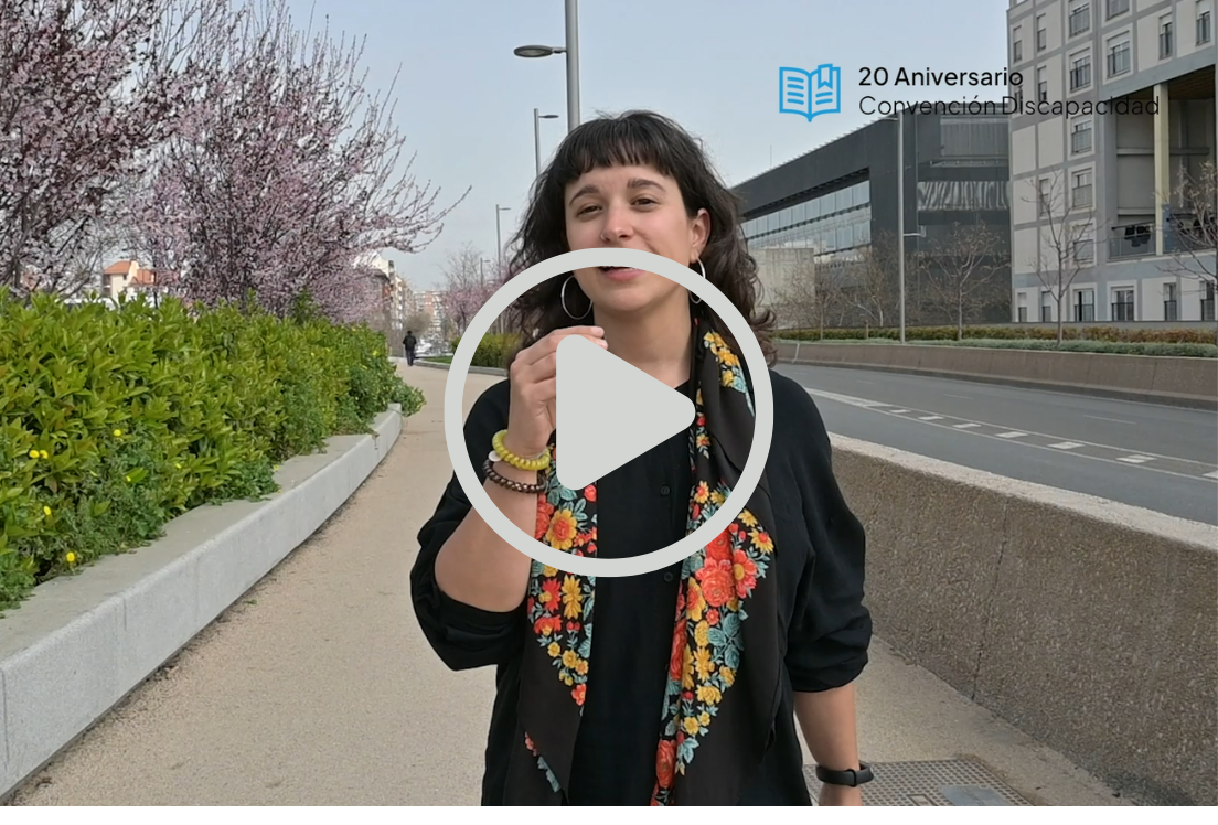 Un mujer en el centro de la imagen con un fondo urbano. Encima de la imagen hay un símbolo de reproducir video.