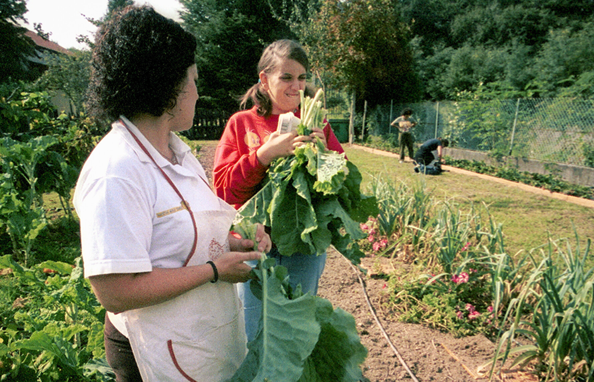 Dos mujeres con autismo recogiendo verduras en un huerto