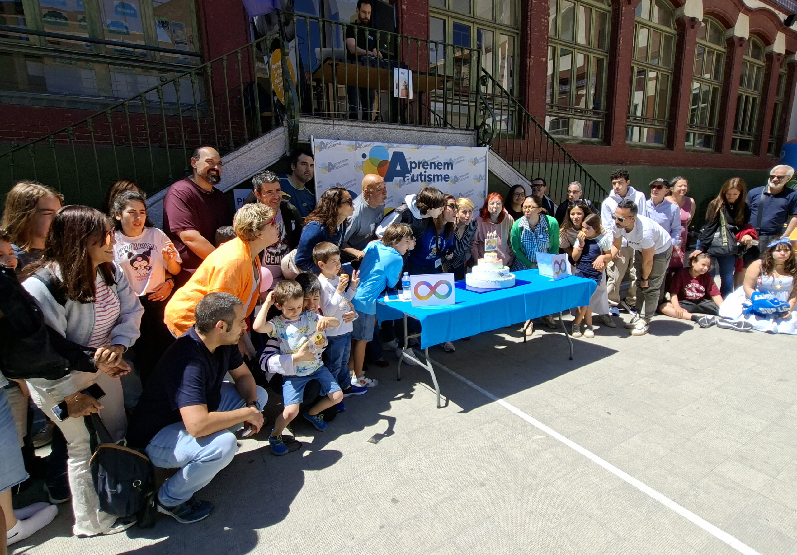 Grupo de personas en la calle posando de pie delante de un cartel en que se lee "Aprenem Autisme"